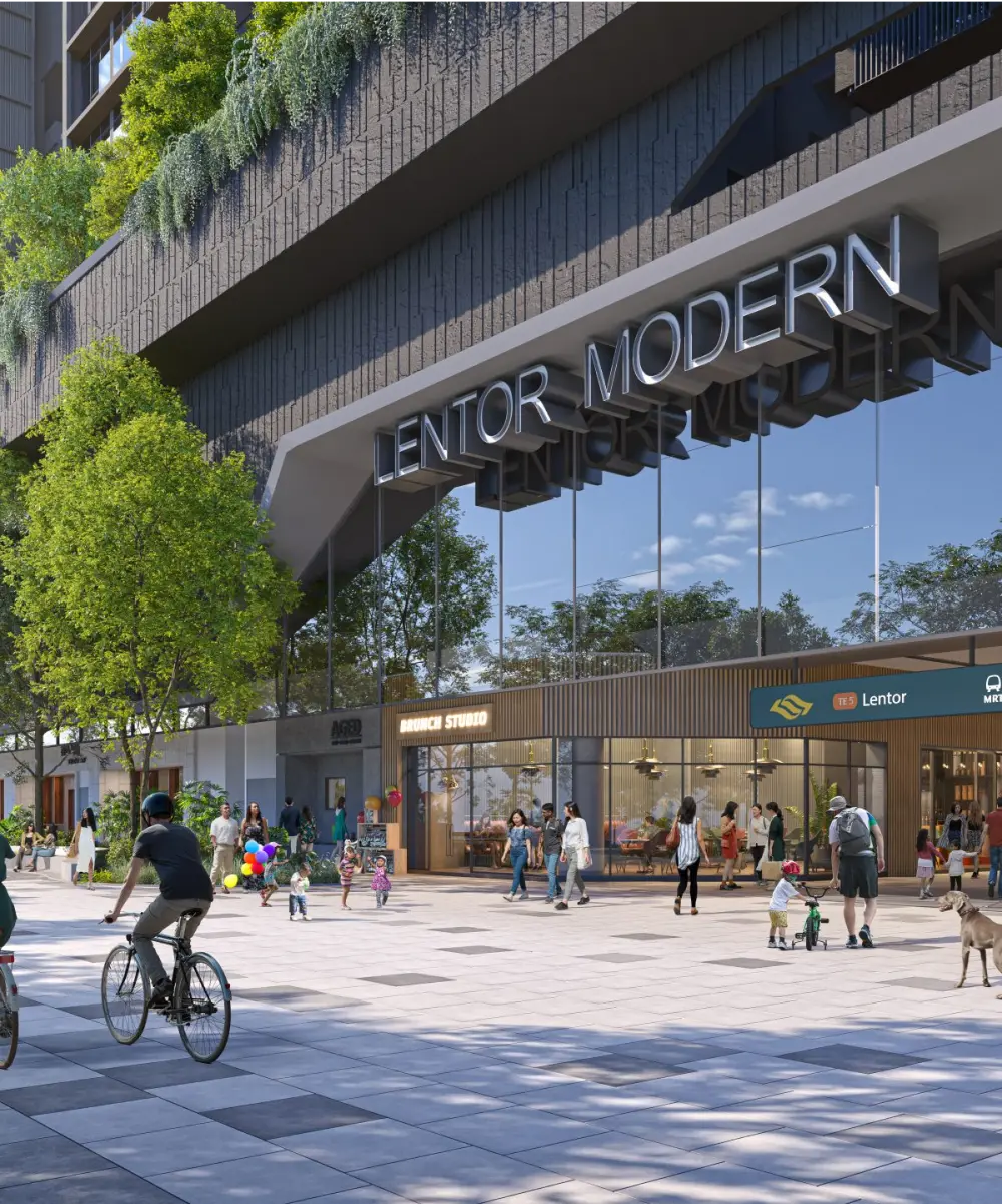 Exterior view of Lentor Modern's retail zone with glass-fronted stores, landscaped greenery, and people engaging in leisurely activities, including cycling and walking.