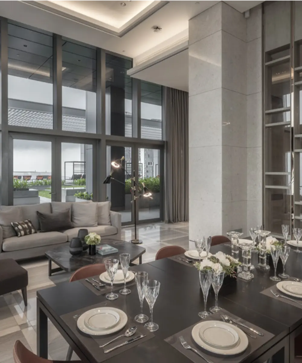 Refined dining room at Wallich Residences featuring a dark wood table set with crystal glassware and elegant plates, overlooking a terrace through large floor-to-ceiling windows.
